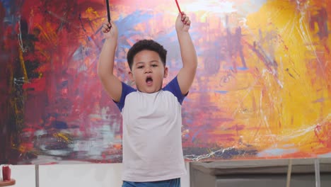 child playing with paintbrushes in art studio