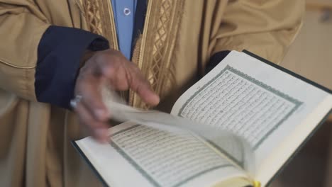 muslim man in traditional clothes reads koran book. opening the sheets of koran to read. the koran, the holy book of muslims all over world