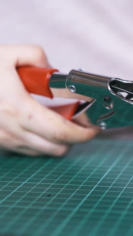 cu: professional tailor makes holes in black leather strip with special punch pliers in workshop close view