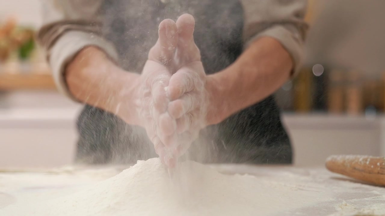 Koch klatscht beim Backen mit mehlbedeckten Händen