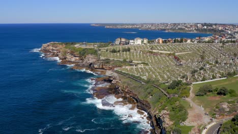 deep blue sea with dangerous waves crashing on cliffs with waverley cemetery at bronte in sydney, new south wales, australia