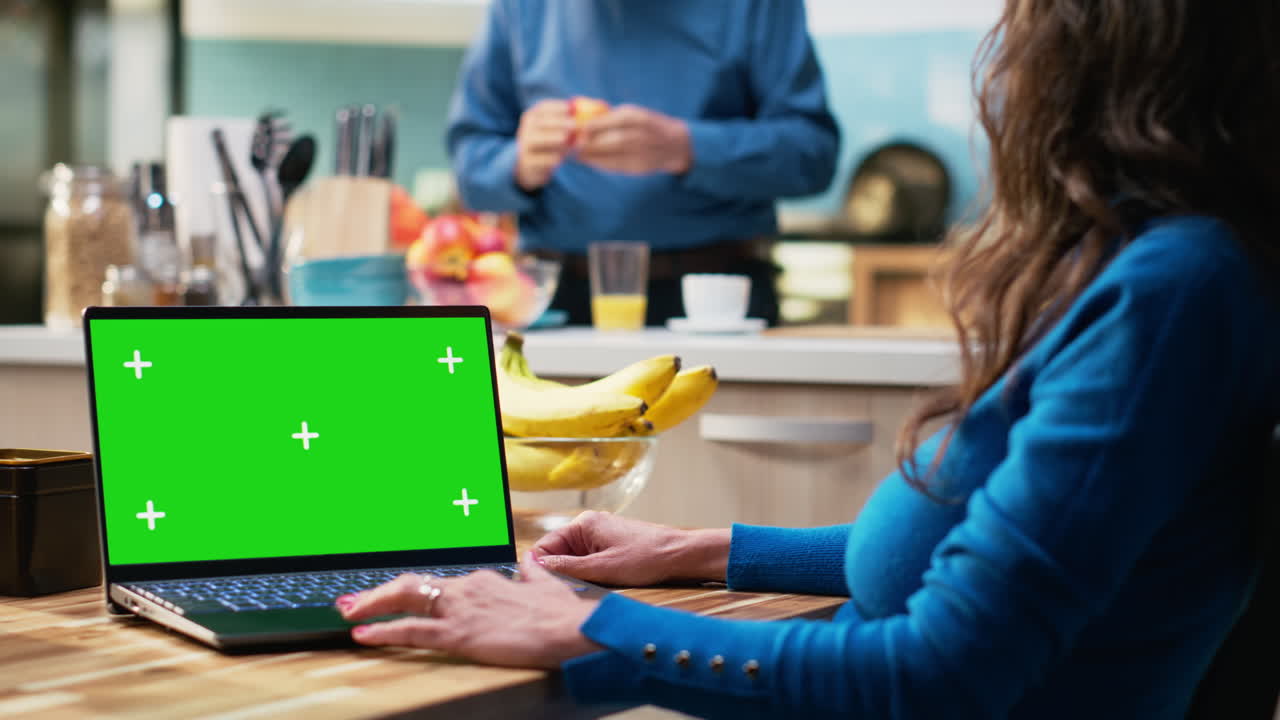 Isolated laptop display with aged woman sitting at the breakfast table