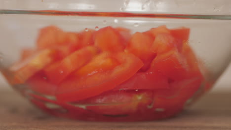 fresh sliced tomatoes pieces being dropped into bowl