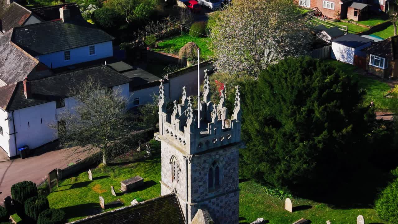 Nærbilde fra luften av et historisk engelsk kirketårn i Great Wishford Wiltshire med omkringliggende landsbyhus, hager og landlige omgivelser i Storbritannia