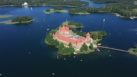 aerial: flying over trakai island castle with a lot of visible boats sailing around on the surface of lake