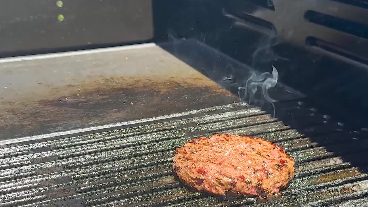 바베큐 그릴에 불꽃으로 버거를 뒤집는 것