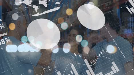 animation of graphs and financial data over happy diverse female and male warehouse workers