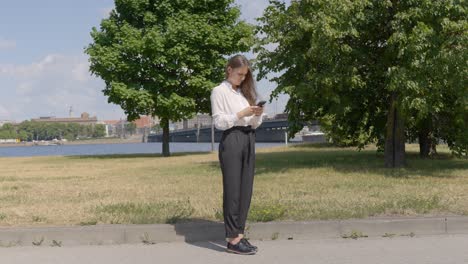 geschäftsfrau schreibt an einem hellen sonnigen tag im park auf ein smartphone