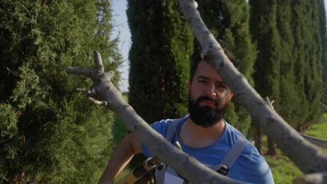 A-man-uses-garden-shears-to-trim-back-tree-branches,-slow-motion-panning-shot