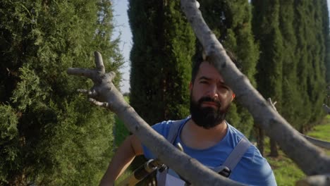 un hombre usa tijeras de jardín para recortar las ramas de los árboles, toma panorámica en cámara lenta