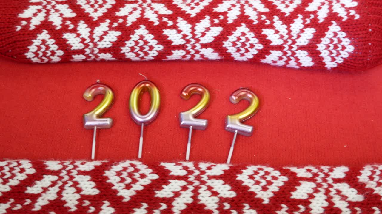 velas de navidad en forma de números 2022 rodeados de guantes acogedores