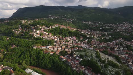 Vista-Aérea-De-La-Ciudad-Construida-En-La-Ladera-Verde-De-La-Montaña,-Cielo-Nublado