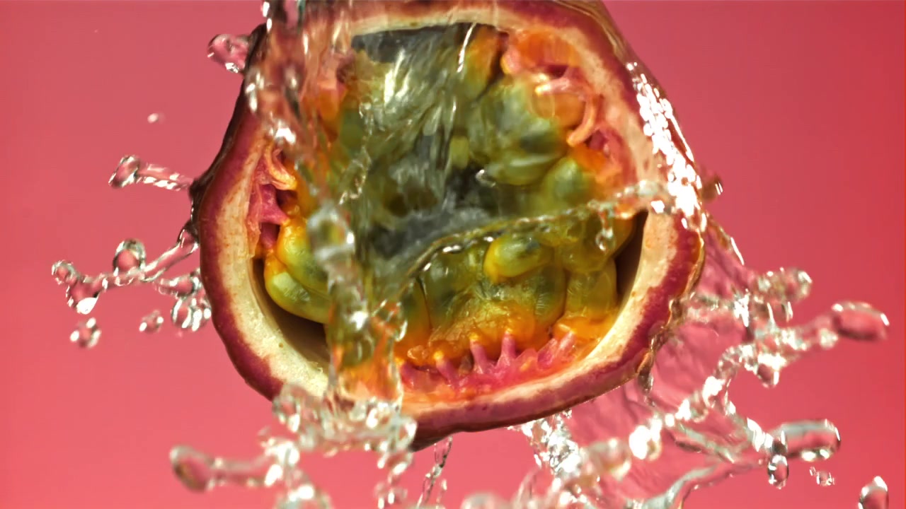 Acqua che schizza al rallentatore su metà di frutto della passione succosa