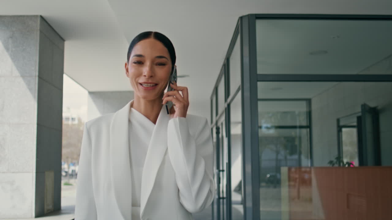 Mladá ředitelka telefonuje, prochází se obchodním centrem. Dáma hovoří.