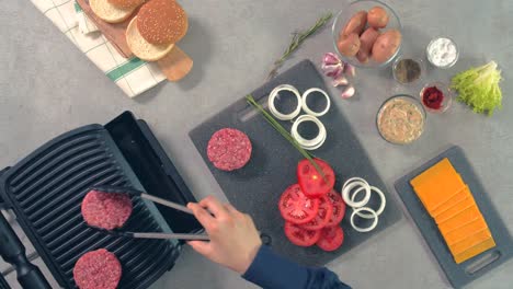 una vista aérea de la carne cruda de hamburguesa que el chef está colocando en la máquina de asar