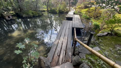 Wooden-bridge-over-a-koi-pond-at-Tenjuan-Buddhist-Temple,-Kyoto,-Japan