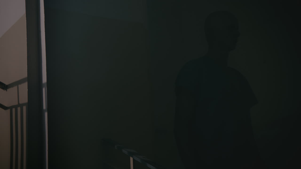A bald man walks on the empty hospital staircase at night