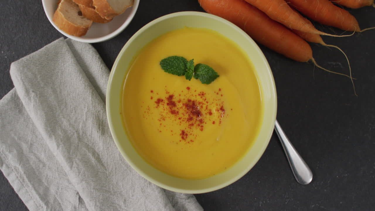 video de sopa de verduras con crema en un cuenco en una mesa gris con zanahorias