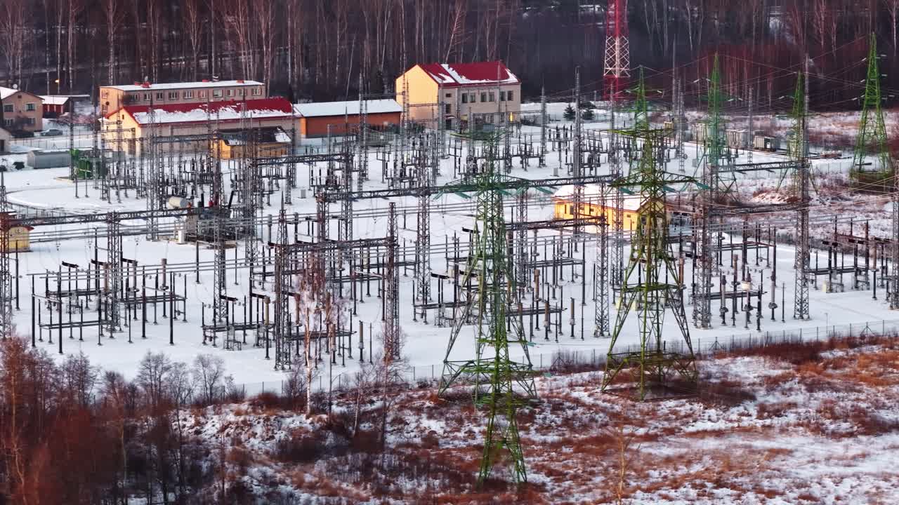 Karla kaplı endüstriyel bir alanda elektrik üreten trafo merkezi, havadan yakın çekim görünümde