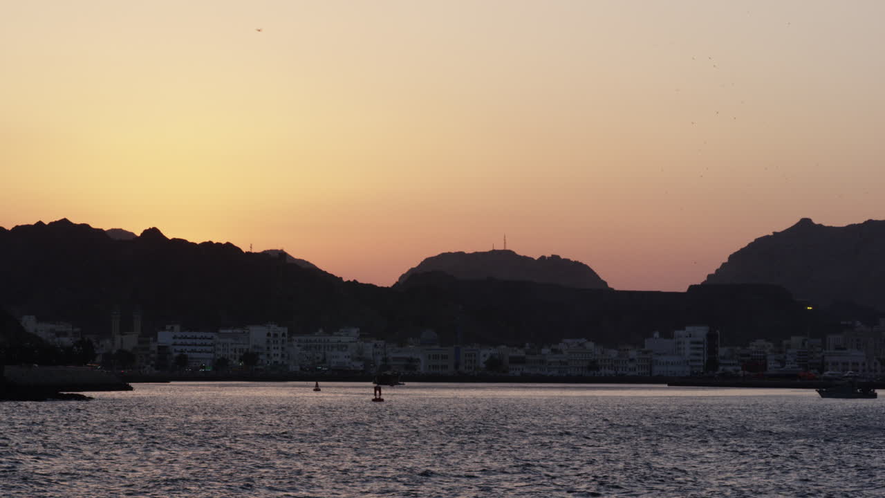 The port of Muscat, Oman across the ocean at sunset, wide shot