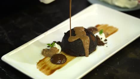 cream being poured over gourmet chocolate pudding dessert