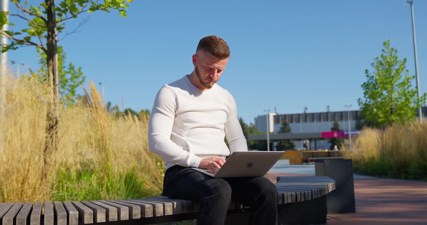 Joven trabajando en un portátil al aire libre en un parque