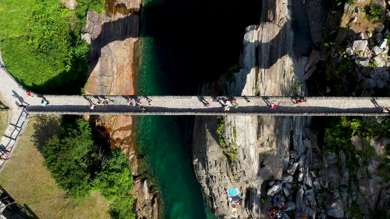 ángulo descendente tiro de drone de ponte dei salti el puente peatonal de piedra medieval de doble arco sobre el agua clara del río verzasca