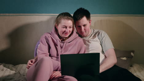 couple watching movie on laptop in bed