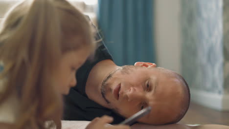 father tired with helping daughter do homework on floor