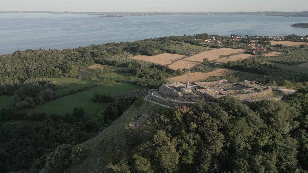Ripresa con drone della Rocca di Manerba del Garda che domina la campagna e il Lago di Garda.