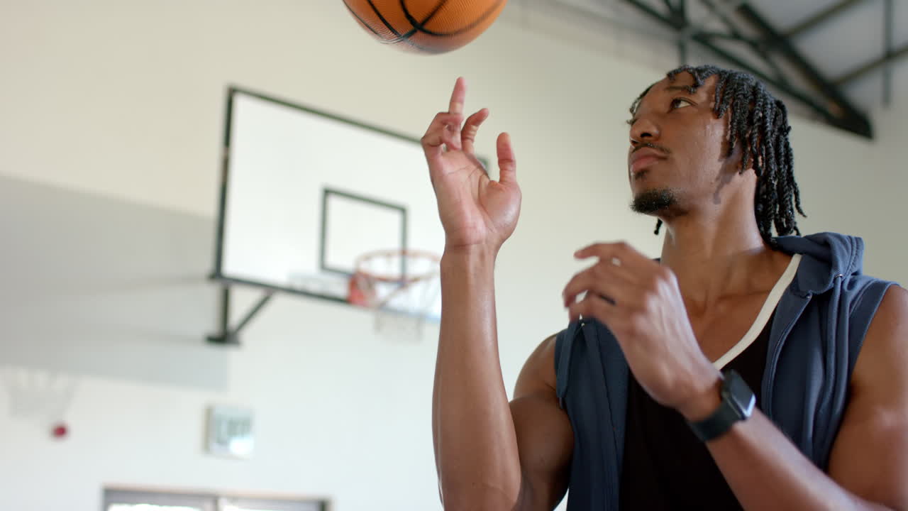 Spinning basketball on finger, man practicing skills in indoor gymnasium