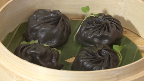 black dumplings in bamboo steamer