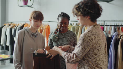 asistente de tienda ayudando a las clientes femeninas multiétnicas con la elección de ropa