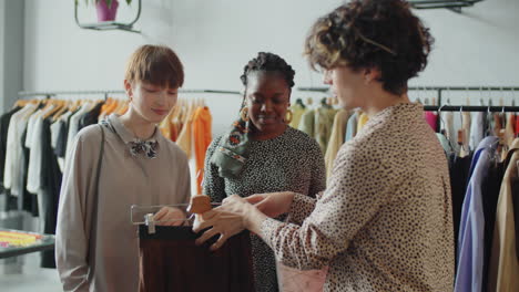 shop assistant helping multiethnic female customers with choosing clothes