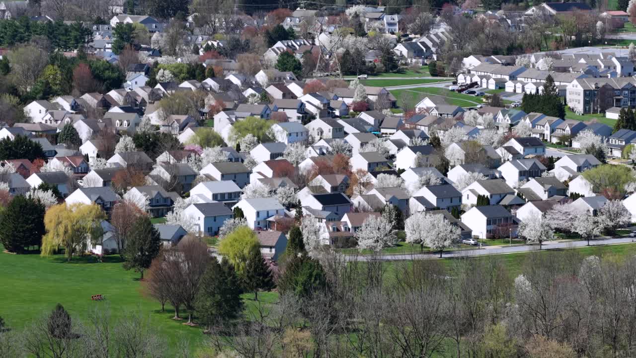 Luftfoto af forstadskvarter i Pennsylvania, USA, med huse med hvide facader, træalléer og blomstrende forårslandskab, der viser fredeligt boligliv set ovenfra.