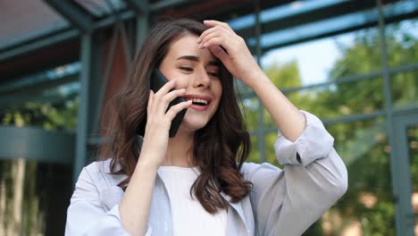 cámara haciendo zoom en una mujer estudiante caucásica hablando en el teléfono inteligente en la calle