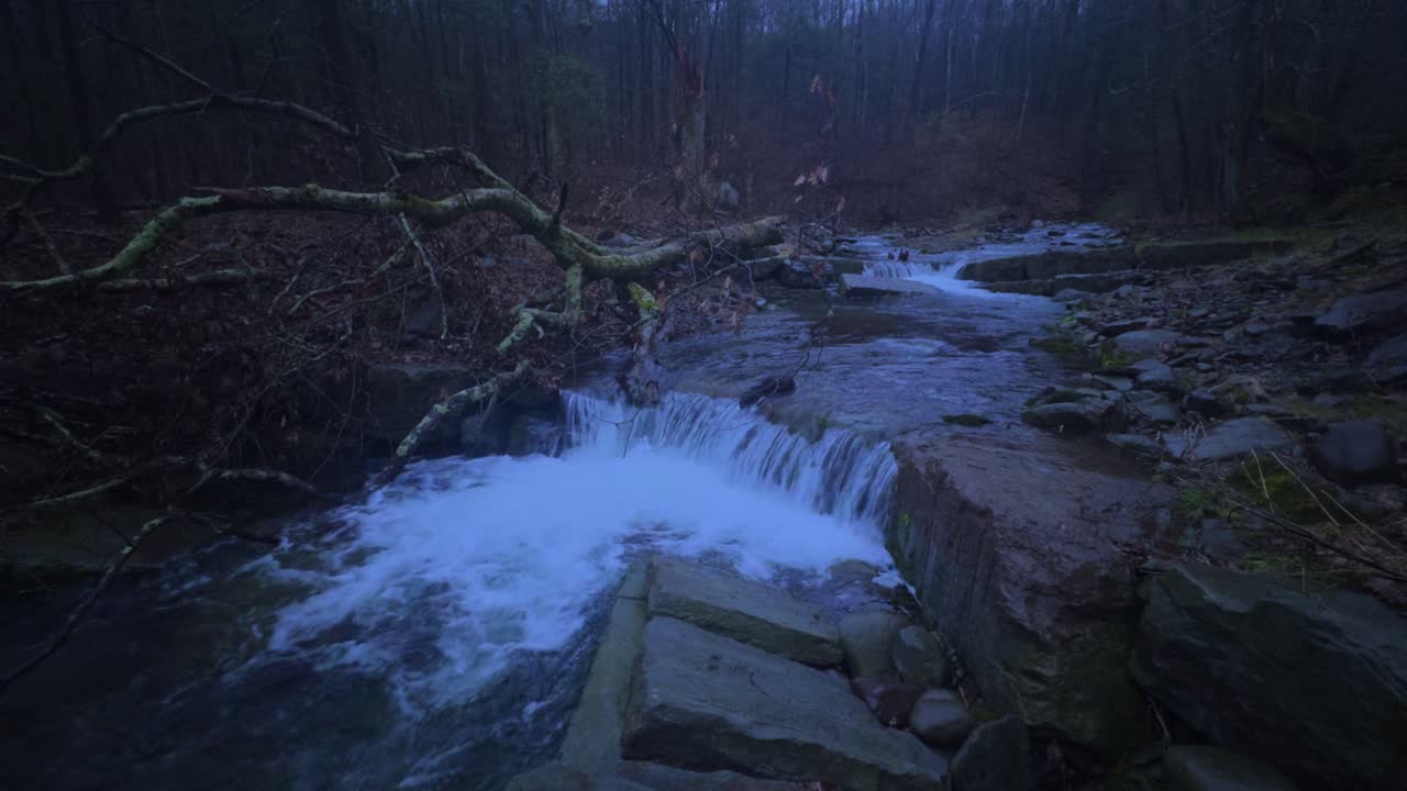 Un ruscello e una cascata boschivi incredibilmente belli e suggestivi sui monti Appalachi durante l'ora blu serale all'inizio dell'inverno
