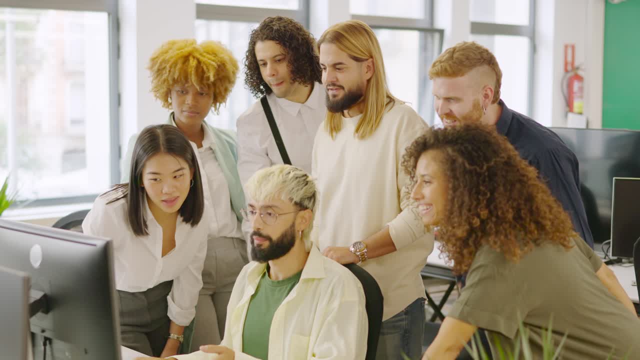 Coworkers talking while looking at a one computer screen