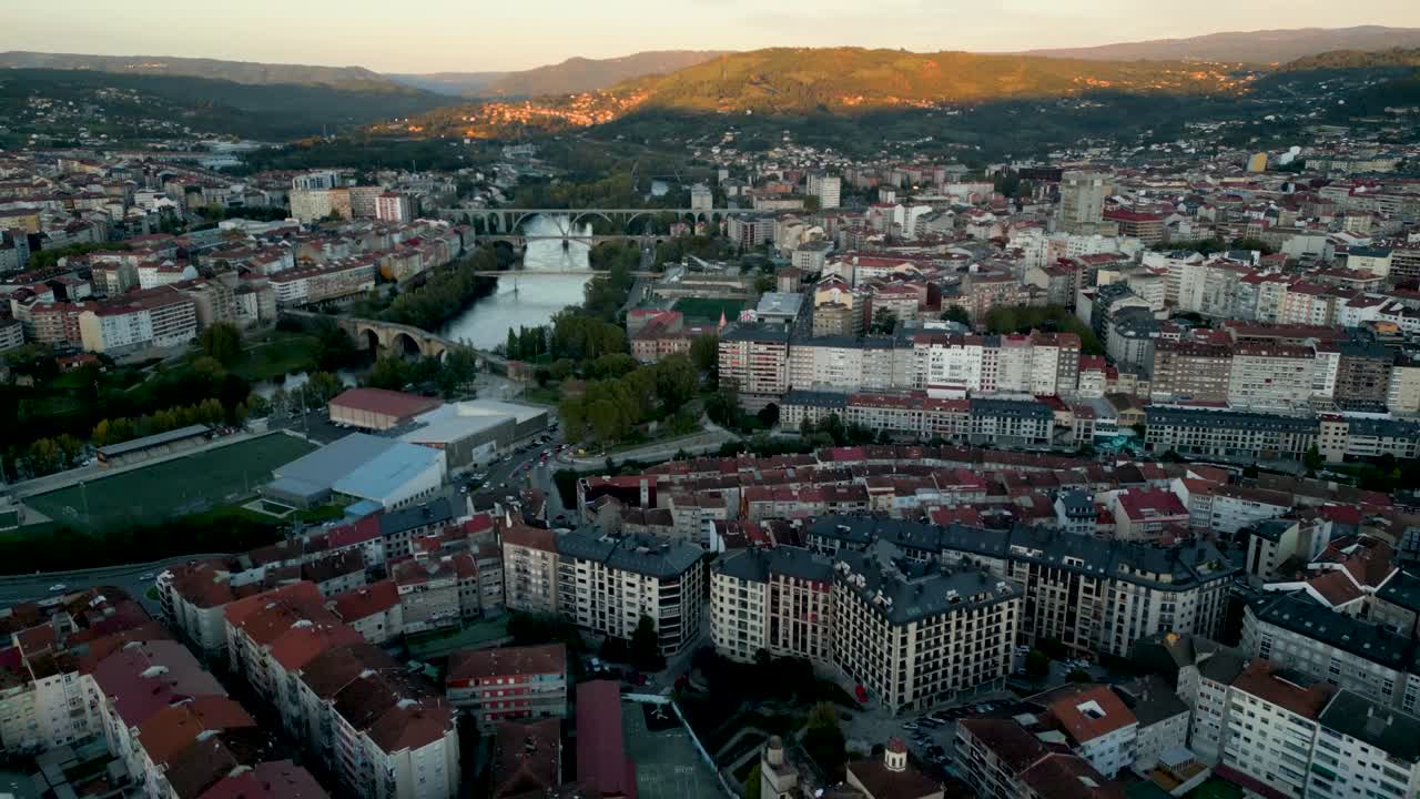 Scenic aerial drone shot of Ourense, Galicia, Spain, with the river winding through the city at sunset, offering a panoramic view