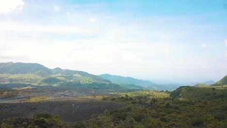 drone aerial flying over a man spinning a staff, standing on a rock with a beautiful volcanic landscape near pacaya volcano, guatemala