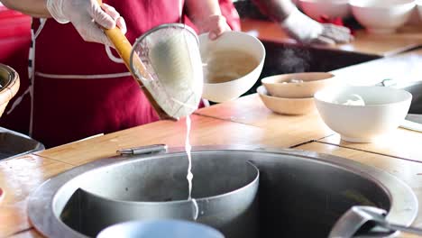 cook prepares noodles in a large pot