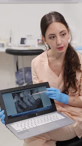 an experienced dentist carefully explains a tablet xray to a patient in a clinical healthcare setting. vertical video.