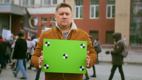 face portrait of activist with green screen banner looking at camera. protest ad