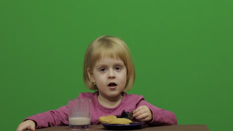 girl sitting at the table and eating chocolate, cookies and drinks cacao