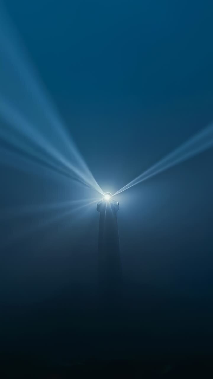 Video verticale: Faro rotante che proietta fasci di luce attraverso una notte costiera nebbiosa, guidando le navi.