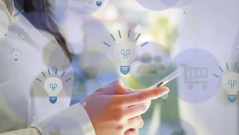 animation of light bulbs and multiple icons over smiling asian woman scrolling on smartphone