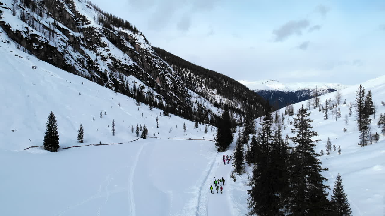 Vista aerea di persone che fanno escursioni e sciano in una valle montana innevata