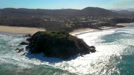 wide rotating drone shot of coastline, small town and rock outcropping at cabarita beach australia
