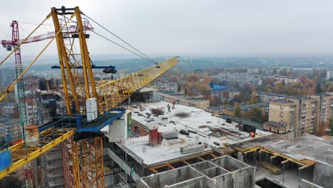 aerial view of construction site in the city. big crane and workers on the roof. construction of new apartment building in progress.