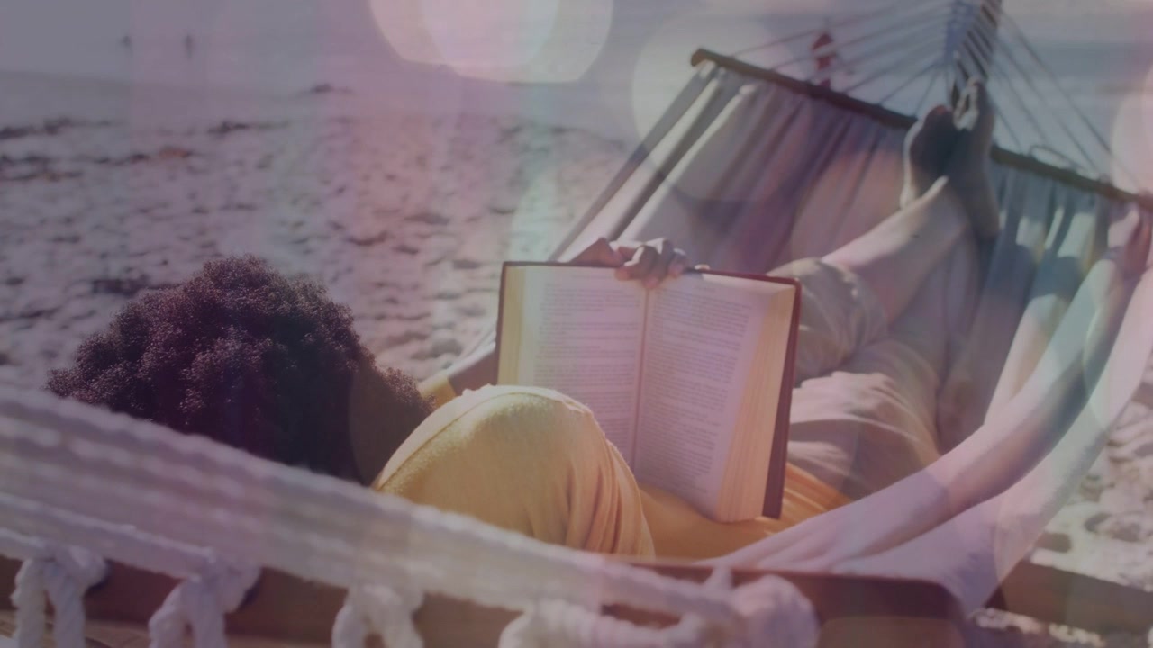 Mulher reclinada em uma rede na areia, segurando um livro e começando a ler, com bokeh flutuante, evocando uma atmosfera de viagem.